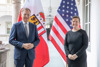 Landeshauptmann Mag. Thomas Stelzer und Melissa Hughes stehen nebeneinander auf einem Gang im Arkadenhof des Linzer Landhauses, hinter ihnen eine Oberösterreich- und eine US-Amerikanische Fahne