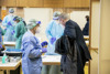 Landeshauptmann Mag. Thomas Stelzer an einem Tisch in einer Teststraße, Desinfektionsmittel, Menschen in Schutzbekleidung