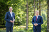 Dr. Heinz Faßmann und Landeshauptmann Mag. Thomas Stelzer nebeneinander vor einem Waldstück mit Bäumen und Sträuchern