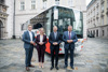 Landesrat Stefan Kaineder, Ministerin Leonore Gewessler, Landeshauptmann Mag. Thomas Stelzer und Landesrat Mag. Günther Steinkellner stehen nebeneinander auf einem Platz vor dem Landhaus, hinter ihnen ein großer Linienbus