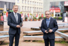 Landeshauptmann Mag. Thomas Stelzer und Landesrat Ing. Wolfgang Klinger mit Handfunkgeräten im Hof des Offenen Kulturhauses in Linz, im Hintergrund Sitzgelegenheiten, Häuser, Gastgärten