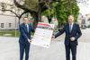 Dr. Johann Lefenda und Landeshauptmann Mag. Thomas Stelzer im Park vor dem Linzer Landhaus, sie halten gemeinsam eine Tafel, auf der die zehn Aktionsfelder illustriert sind 