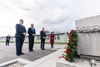 (v.l.) Oskar Deutsch, Präsident der Israelitischen Religionsgesellschaft Österreich (IRG), Innenminister Karl Nehammer, Landeshauptmann Thomas Stelzer und Barbara Glück, Direktorin des Mauthausen Memorial, stehen vor einem Mahnmal in der KZ-Gedenkstätte in Mauthausen, im Hintergrund eine Baracke. 