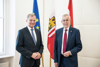 Landeshauptmann Mag. Thomas Stelzer und Bundespräsident Dr. Alexander Van der Bellen stehen nebeneinander vor einer EU-, Oberösterreich- und Österreich-Fahne