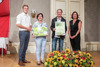 Landesrat Stefan Kaineder, Katharina Zauner, Peter Klein und Barbara Binder stehen nebeneinander und halten Preis und Urkunde, vor ihnen ein großes herbstliches Blumengesteck 