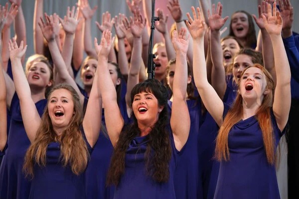Frauenchor beim Singen, die Sängerinnen strecken ihre Hände über den Kopf 