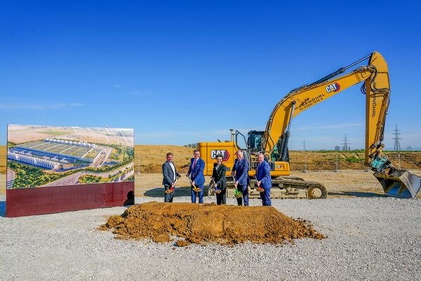Christoph Lichtenauer, Bürgermeister Hargelsberg, Wirtschafts-Landesrat Markus Achleitner, Christine Antlanger-Winter, Country Director Google Österreich & Schweiz, Landeshauptmann Mag. Thomas Stelzer und Christian Kolarik, Bürgermeister Kronstorf beim Spatenstich vor einem Bagger und neben einer Visualisierung, wie das fertige Rechenzentrum aus schräger Vogelperspektive aussehen wird.