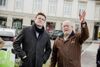 Landesrat Stefan Kaineder und Franz Baumann stehen nebeneinander auf einem Stadtplatz mit Gebäuden, parkende Autos