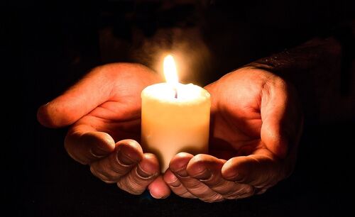 Hände halten eine Kerze in der Dunkelheit