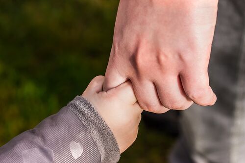 Hand eines Erwachsenen hält eine Kinderhand