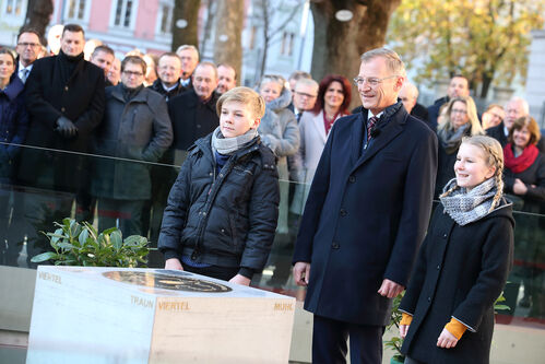 Landeshauptmann Mag. Thomas Stelzer mit den Kindern Rosalie Nova und Levin Börner vor dem Gedenkstein