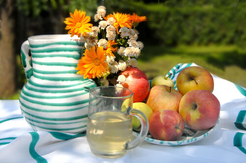 Äpfel in einer Schüssel, Krug, Glas mit Apfelsaft, Blumendekoration