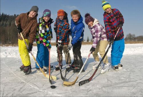 Kinder spielen Eishockey auf zugefrorenem See
