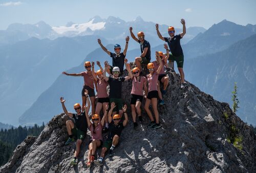 Jugendliche winken von einem Berggipfel in die Kamera