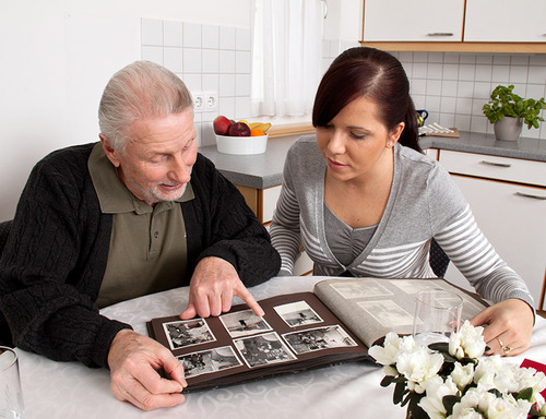 Frau schaut mit Senioren Fotoalbum an