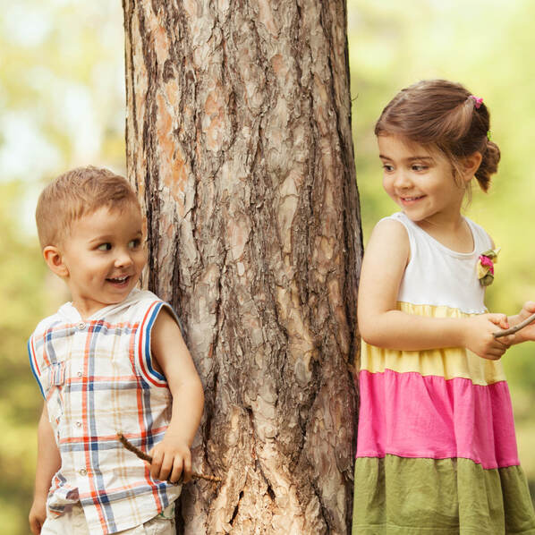 Zwei Kinder lehnen an einem Baumstamm