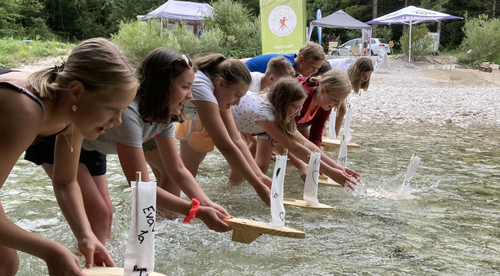 Kinder setzen ihre selbst gebauten Holzboote ins Wasser