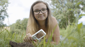 Nicole erforscht das Bodenleben mit der Lupe.