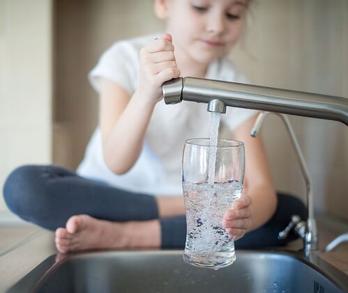 Mädchen mit einem Glas Wasser in der Küche