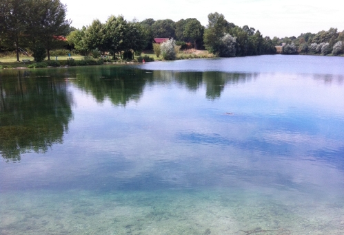 Badesee Pupping mit klarem Wasser auf dem sich blauer Himmel und weiße Wolken spiegeln