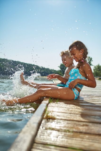 Kinder am Stegrand plantschen mit Beinen im Wasser