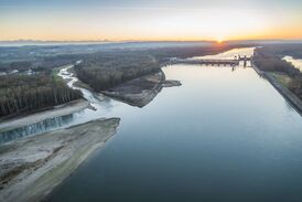 Das Laufkraftwerk Ottensheim-Wilhering (im Hintergrund) an der Donau, links die Einmündung des Innbaches mit längster Fischwanderhilfe Europas über das Innbach-Aschach-Gerinne sowie der Donau-Nebenarm Marktau 