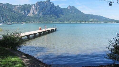 Mondsee bei Loibichl mit langem Holzsteg mit sitzendem Badegast