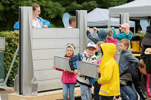 Kinder beim Aufstellen einer Hochwasserschutzwand.