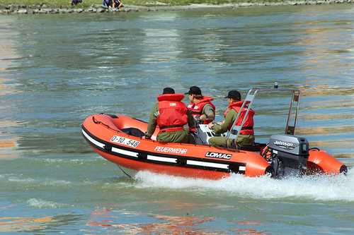 Drei Feuerwehrmänner im Motorboot 