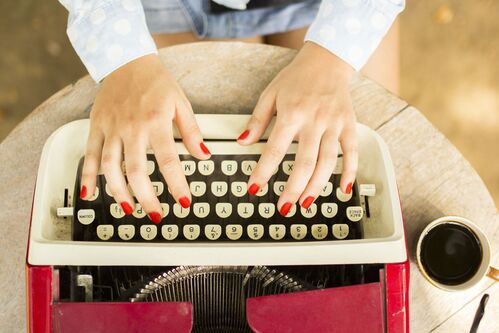 Person tippt auf einer Schreibmaschine