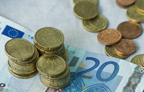 Mehrere Euro und Cent Münzen stappeln sich auf einem 20 Euro Schein