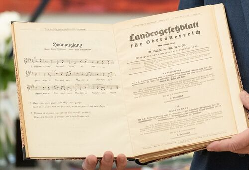 LH Mag. Stelzer hält das originale Landesgesetzblatt, mit dem der „Hoamatgsang“ damals offiziell zur oö. Landeshymne erklärt wurde, in seinen Händen.