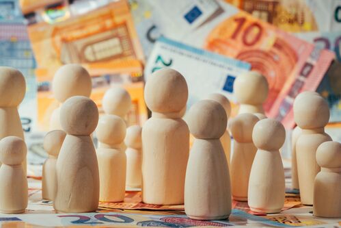 Mehrere Holzfiguren stehen auf mehreren Euroscheinen. Mehrere Holzfiguren stehen auf mehreren Euroscheinen.