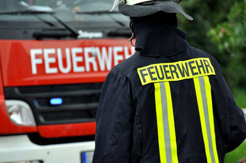 Feuerwehrmann trägt eine Jacke  mit der Aufschrift 