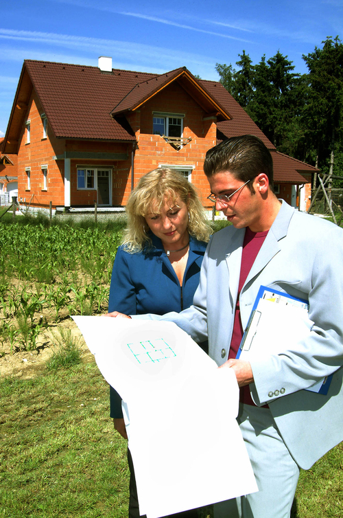Architekt mit Bauherrin vor einem Rohbau 